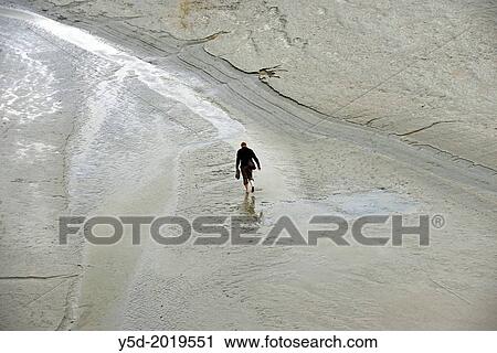 Lonely man walking barefoot in shallow waters around Mont Saint-Michel, Normandy, France View Large Photo Image Stock Image - Lonely man walking barefoot in shallow waters around Mont Saint-Michel, Normandy, France. Fotosearch