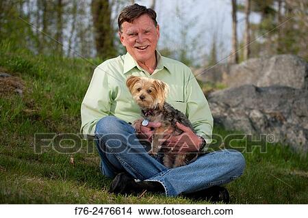 Man in blue jeans (MR# G120513, sitting on lawn in front of his home, holding his small yorkshire terrier. View Large Photo Image Picture - Man in blue jeans (MR# G120513, sitting on lawn in front of his home, holding his small yorkshire terrier.. Fotosearch