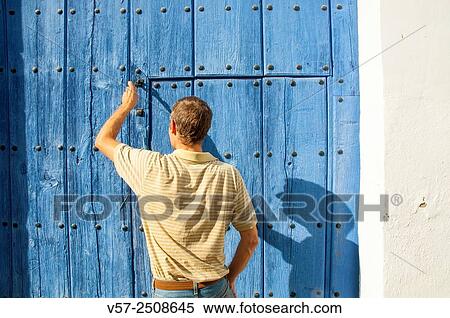 Stock Photography - Man knocking at wooden door. Almagro, Ciudad Real province, Castilla La Mancha, Spain.. Fotosearch