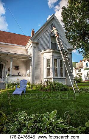 Man on ladder painting upper story of single family home in Lancaster, NH, USA View Large Photo Image Stock Photography - Man on ladder painting upper story of single family home in Lancaster, NH, USA. Fotosearch