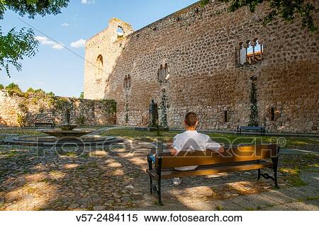 Stock Photography - Man sitting on a bench next to the ruins of the castle. Brihuega, Guadalajara province, Castilla La Mancha, Spain.. Fotosearch