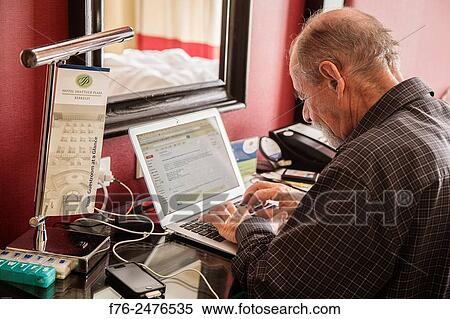 Man working on laptop attached to the internet in a hotel room in Berkeley, CA, MR# 6117. View Large Photo Image Stock Photography - Man working on laptop attached to the internet in a hotel room in Berkeley, CA, MR# 6117.. Fotosearch