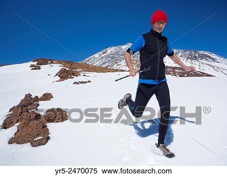 Stock Photography - Mature runner training at altitude in Teide National Park on Tenerife, Canary Islands, Spain. Mount Teide in background.. Fotosearch