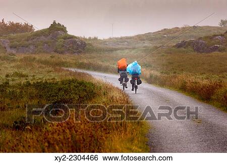 Stock Photograph - near Derrylea, County Kerry, Republic of Ireland. Eire. Ecotourism. Two touring cyclists press on through the rain in a wild Kerry landscape.. Fotosearch