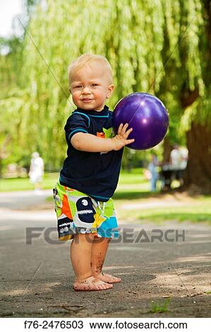 One year old boy, standing barefoot in a park, holding purple plastic ball. MR# 6155. View Large Photo Image Stock Image - One year old boy, standing barefoot in a park, holding purple plastic ball. MR# 6155.. Fotosearch