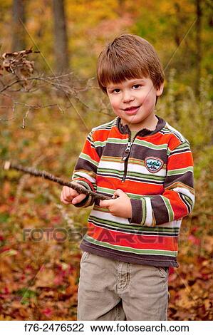 Portrait of a 3 year old boy holding a stick while standing outdoors in the fall. View Large Photo Image Stock Image - Portrait of a 3 year old boy holding a stick while standing outdoors in the fall.. Fotosearch