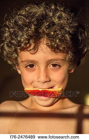 Portrait of a smiling 7 year old boy with an apple wedge in his mouth, mr# 6302. View Large Photo Image Stock Photo - Portrait of a smiling 7 year old boy with an apple wedge in his mouth, mr# 6302.. Fotosearch