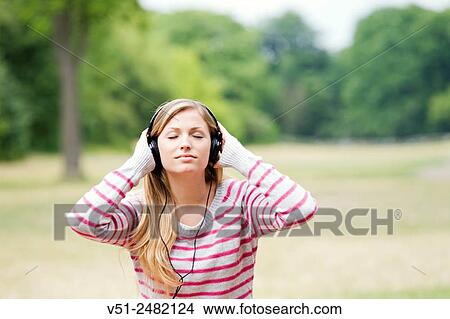 Portrait of a woman with closed eyes listening to music in the park View Large Photo Image Picture - Portrait of a woman with closed eyes listening to music in the park. Fotosearch