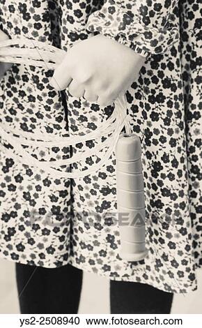 Stock Image - Portrait of little girl in dress with flowers. She is holding a jump rope in her hands.. Fotosearch