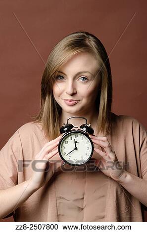 Punctual young woman holding an alarm clock. View Large Photo Image Stock Image - Punctual young woman holding an alarm clock.. Fotosearch