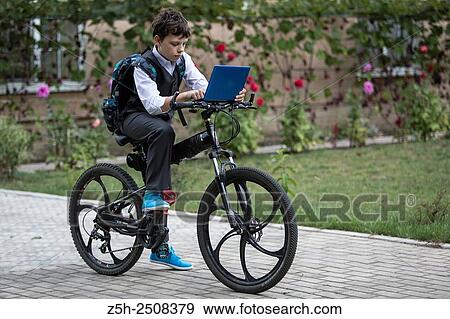 Stock Photo - Russia. Belgorod region. Tavrovsky rural settlement. The village Solomino. Boy on bike rides to school.. Fotosearch