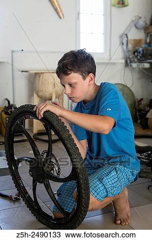 Stock Image - Russia. Belgorod region. The boy in the garage making repairs bicycles.. Fotosearch