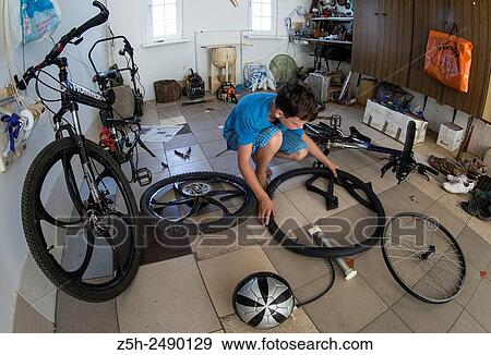 Stock Photo - Russia. Belgorod region. The boy in the garage making repairs bicycles.. Fotosearch