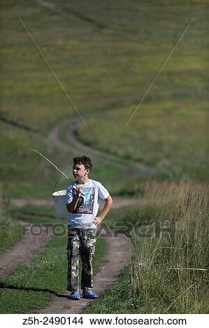Picture - Russian Federation. Belgorod region. The boy goes on a fishing trip on the country road.. Fotosearch