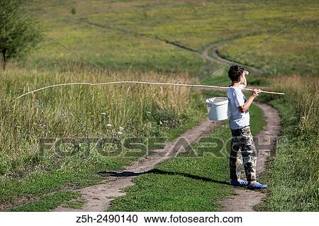 Stock Image - Russian Federation. Belgorod region. The boy goes on a fishing trip on the country road.. Fotosearch