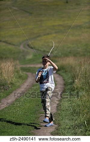 Stock Image - Russian Federation. Belgorod region. The boy goes on a fishing trip on the country road.. Fotosearch