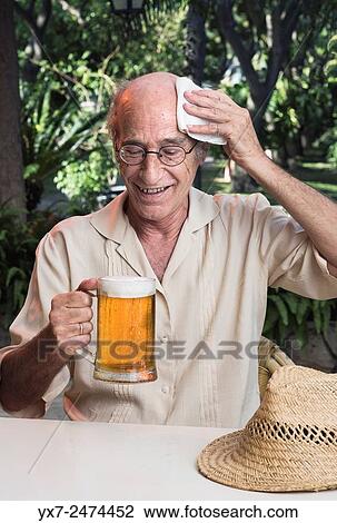 Stock Image - Senior man on a hot day holding a beer.. Fotosearch
