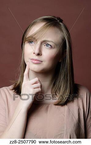 Stock Image - Serious young woman hand on face trying to remember.. Fotosearch