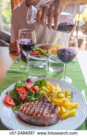Sirloin steak with salad and chips, and man pouring red wine in a glass. View Large Photo Image Stock Photo - Sirloin steak with salad and chips, and man pouring red wine in a glass.. Fotosearch