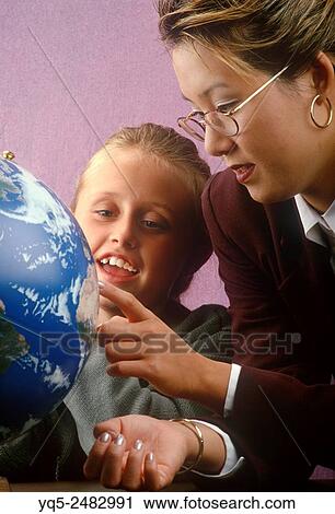 Stock Image - teacher and student looking at globe.. Fotosearch