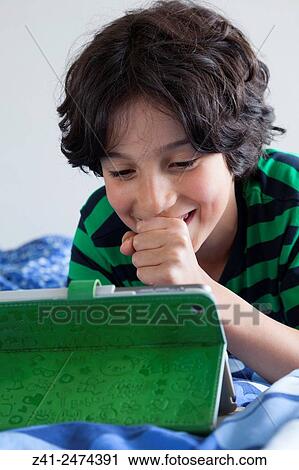 Teenage boy looking surprised at his digital tablet. View Large Photo Image Stock Image - Teenage boy looking surprised at his digital tablet.. Fotosearch