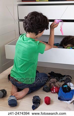 Picture - Teenage boy making a mess while searching into his wardrobe drawer.. Fotosearch