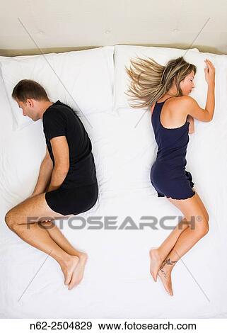 Unhappy couple sleeping far away from each other on bed top view. View Large Photo Image Stock Photo - Unhappy couple sleeping far away from each other on bed top view.. Fotosearch