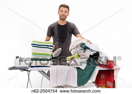 Very sweaty man behind a ironing board full of clothing looks smugly. View Large Photo Image Picture - Very sweaty man behind a ironing board full of clothing looks smugly.. Fotosearch
