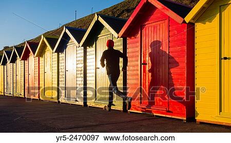 Whitby, North Yorkshire, England, United Kingdom. Europe. Mature jogger passing beach huts on Whitby beach just after sunrise. View Large Photo Image Stock Photo - Whitby, North Yorkshire, England, United Kingdom. Europe. Mature jogger passing beach huts on Whitby beach just after sunrise.. Fotosearch