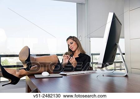 Woman in office filing nails in front of the coumputer with legs on the table View Large Photo Image Stock Image - Woman in office filing nails in front of the coumputer with legs on the table. Fotosearch