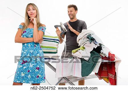 Woman very happy with her arms folded behind her a sweaty man with hysterical expression controls the temperature of the iron as many clothes ironing required. View Large Photo Image Stock Image - Woman very happy with her arms folded behind her a sweaty man with hysterical expression controls the temperature of the iron as many clothes ironing required.. Fotosearch