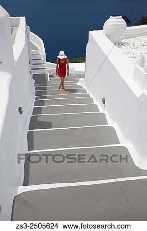 Picture - Woman walking up the steps in Oia town, Santorini, Cyclades Islands, Greek Islands, Greece, Europe.. Fotosearch