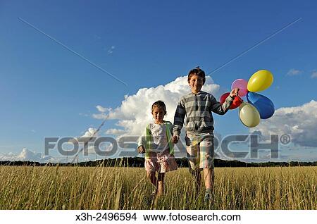 young boy with his sister running with balloons in a field, Ile-de-France, France, Europe. View Large Photo Image Picture - young boy with his sister running with balloons in a field, Ile-de-France, France, Europe.. Fotosearch