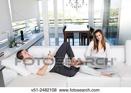 Young couple enjoying leisure at home View Large Photo Image Stock Photo - Young couple enjoying leisure at home. Fotosearch