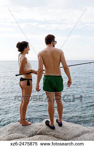 Stock Photography - Young couple fishing at sea in the morning, Tossa de Mar, Catalonia, Spain, Europe.. Fotosearch