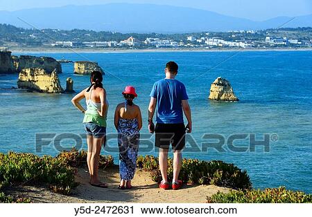Stock Image - young family admiring view from Ponta da Piedade, Meia Praia in background, Atlantic Ocean, Lagos, Algarve, Portugal, Europe. Fotosearch