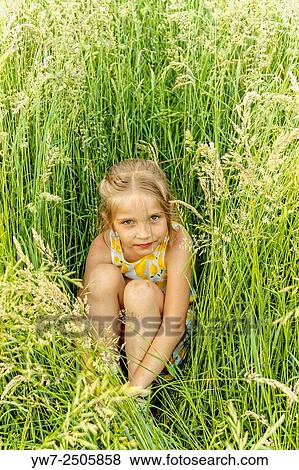 Young girl sitting in the grass, Poland. View Large Photo Image Stock Photo - Young girl sitting in the grass, Poland.. Fotosearch