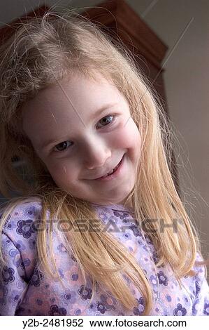 Stock Image - Young girl with long blond hair smiles shyly. Fotosearch