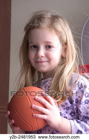 Young girl with long blond hair smiles as she holds a small basketball View Large Photo Image Stock Image - Young girl with long blond hair smiles as she holds a small basketball. Fotosearch