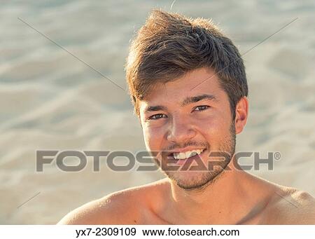 Stock Photo - Young man at the beach smiling.. Fotosearch