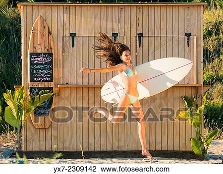 Stock Image - Young teenager with her surf board at the beach. Tarifa, Cadiz, Costa de la Luz, Andalusia, Spain.. Fotosearch