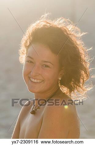 Stock Photograph - Young woman at the beach smiling.. Fotosearch