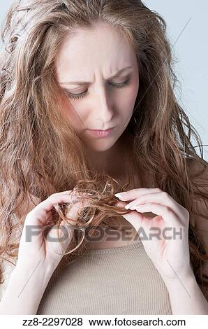 Stock Photo - Young woman checking her hair for split ends.. Fotosearch