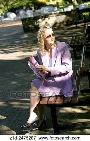 Stock Photo - young woman reading in a park enjoying summer sun.. Fotosearch