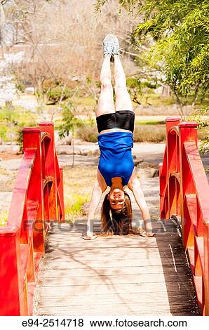 A 22 year old brunette woman doing a handstand on a foot bridge in a garden. View Large Photo Image Stock Photo - A 22 year old brunette woman doing a handstand on a foot bridge in a garden.. Fotosearch