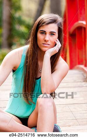A 22 year old brunette woman looking directly at the camera sitting on a foot bridge in a garden setting. View Large Photo Image Stock Photograph - A 22 year old brunette woman looking directly at the camera sitting on a foot bridge in a garden setting.. Fotosearch