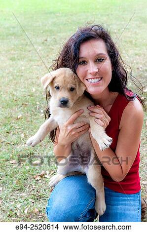 A 38 year old brunette woman holding a young puppy on a farm. View Large Photo Image Picture - A 38 year old brunette woman holding a young puppy on a farm.. Fotosearch