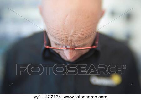 A bald man with glasses working in a store. View Large Photo Image Picture - A bald man with glasses working in a store.. Fotosearch