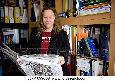 A young female professional reading a Russian newspaper in font of her library. View Large Photo Image Stock Photo - A young female professional reading a Russian newspaper in font of her library.. Fotosearch