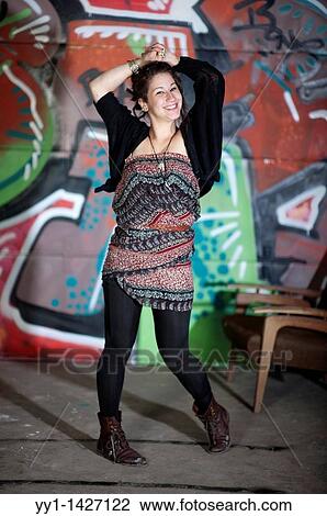 Stock Image - A young woman posing in front of a graffity.. Fotosearch